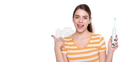 Téléchargez les photos : Heureuse jeune femme avec brosse à dents électrique isolé sur fond blanc. pouce levé. - en image libre de droit