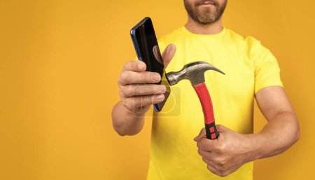 photo of hack the phone screen with hammer, advertisement. hack the phone screen isolated on yellow. hack the phone screen on background. hack the phone screen in studio.
