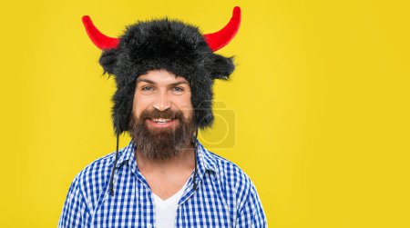 Photo for Bearded and brutal hipster. Caucasian happy guy in bull hat. Happy man with beard. Brutal man wearing bull hat isolated on yellow. Bearded man in party hat. Copy space banner advertisement. - Royalty Free Image