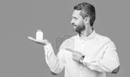 Photo for Man point finger on medication jar. photo of man holding medication, healthcare. man with medication isolated on blue background. man hold medication in studio. - Royalty Free Image
