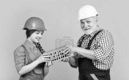 glückliches Mädchen und Großvater Maurer in Helm auf gelbem Hintergrund.