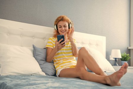 happy woman in headphones relax with phone. woman relax at home listen to music in headphones. woman relax listening music.