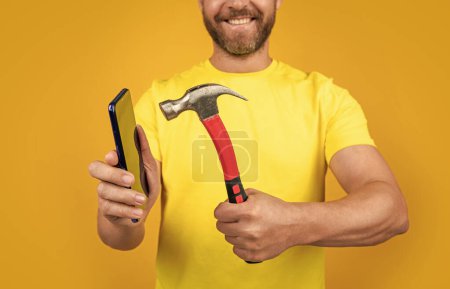 selective focus of hack the phone screen isolated on yellow. hack the phone screen on background. hack the phone screen in studio. photo of hack the phone screen with hammer.