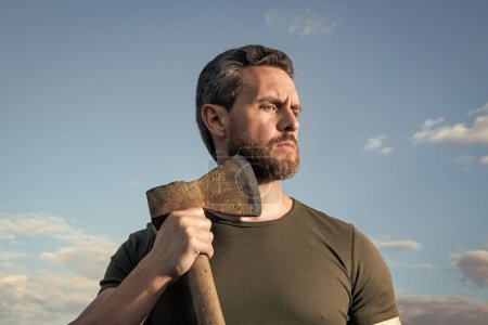 bearded man with axe. caucasian man hold ax. brutal man on sky background.