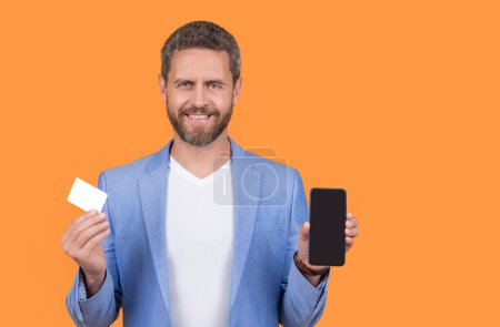 ecommerce concept. happy man paying online, ecommerce. man paying online hold phone and ecommerce card with copy space. man paying ecommerce online isolated on yellow. man paying online in studio.
