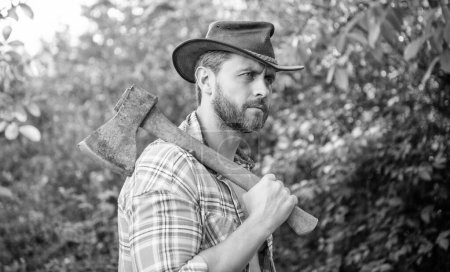 rancher with axe outside. rancher with axe wearing checkered shirt. rancher with axe outdoor. photo of rancher with axe.
