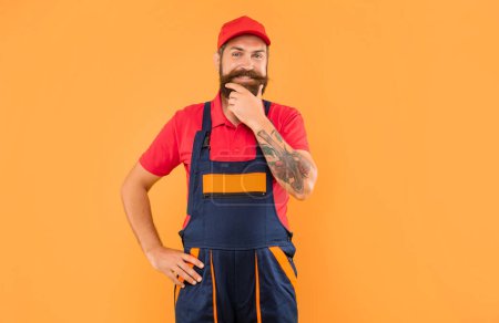 cheerful bearded man repairer in work clothes on yellow background.