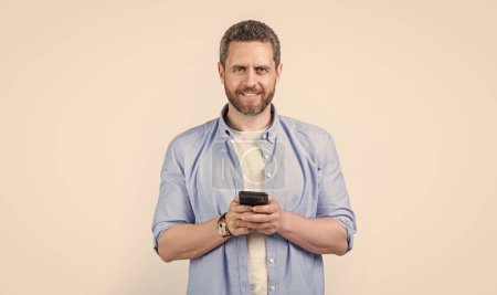 Photo for Cheerful man write message on phone isolated on studio background. man with phone message in studio. message on man phone. photo of man texting phone message. - Royalty Free Image