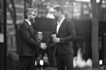 Photo for Happy two business partners dealing negotiation. two business partners dealing negotiation outdoor. two business partners hold coffee dealing negotiation. photo of two business partners dealing. - Royalty Free Image