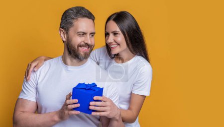 Loving woman giving present for Valentines day. Gift box to surprised man. Boyfriend receiving present from girlfriend. Valentines day couple. Couple in love. Mans day gift. True sentiments.