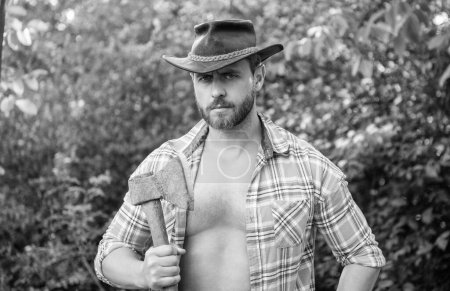 lumberjack with axe wearing unbuttoned checkered shirt. lumberjack with axe outdoor. photo of lumberjack with axe. lumberjack with axe.