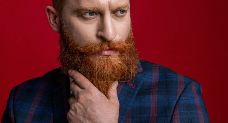 Man wear elegant formal menswear. Elegance of bearded gentleman in formal suit. Formalwear. Tux man in formalwear isolated on red. Redhead man in formalwear tuxedo. Stylish beard.