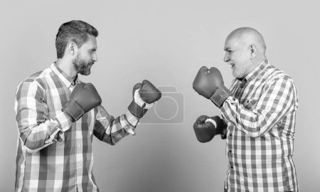 cheerful generation men boxing on background. photo of generation men boxing wear checkered shirt. two generation men boxing isolated on yellow. generation men boxing in studio.