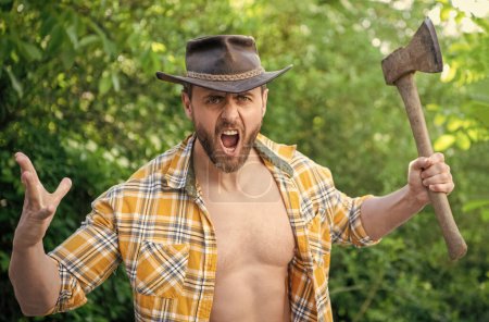 shouting angry lumberjack with axe wearing checkered shirt. angry lumberjack with axe outdoor. photo of angry lumberjack with axe. angry lumberjack with axe.
