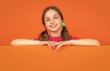 Positives Kind hinter orangefarbenem Papier mit Kopierplatz für Werbung.