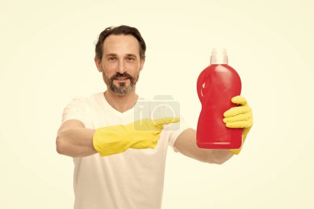 Mann zeigt mit dem Finger auf Waschmittel isoliert auf weiß. Mann mit Waschmittel im Studio. Mann mit Waschmittel im Hintergrund. Foto eines Mannes mit Waschmittelflasche.