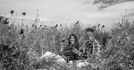 couple in love of man and woman drink red wine in summer poppy flower field, relax.