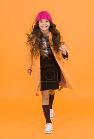 Keep moving. Adorable schoolgirl winter outfit. Schoolgirl daily outfit with backpack. Fashion accessory. Fancy schoolgirl. Girl little fashionable pupil wear knitted hat and jacket. Modern outfit.