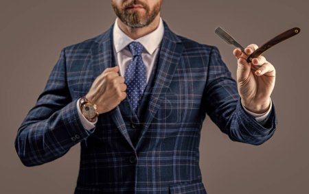 selective focus of barber man hold blade isolated on grey background. barber man with razor blade. man with blade in barber studio. photo of bearded man with barber blade.