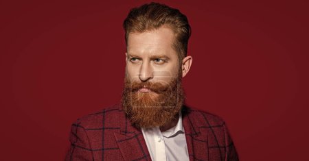 face of man in formalwear suit on background. photo of man in formalwear suit with beard. man in formalwear suit isolated on red. man in formalwear suit at studio.