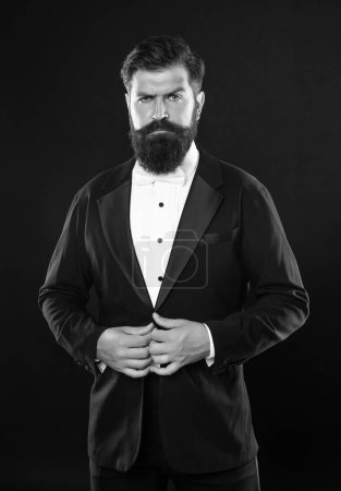 brutal gentleman in tuxedo on black background, formalwear.