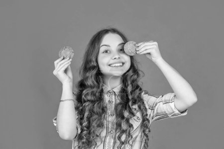positive teen girl with oatmeal cookies on orange background.