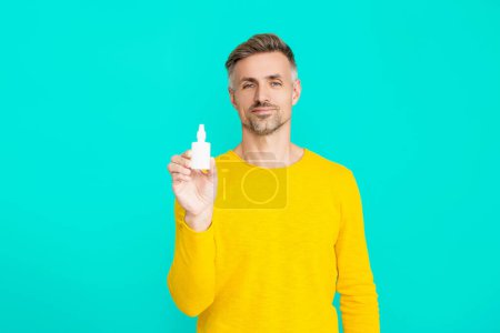 Medicine and health care. Medical spray or drops. Man with nasal or eyecare medication. Man offering a nasal spray. Nasal irrigation. Treatment of a runny nose. Rhinitis.
