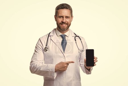 medical application. cheerful man doctor presenting medical phone application. emedicine in your phone.