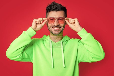 happy cool fancy man isolated on red background. cool fancy man in studio. cool fancy man wearing glasses. photo of cool fancy man.