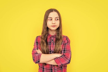 photo of teen girl with long hair wearing checkered shirt. teen girl isolated on yellow. teen girl in studio. teen girl on background.