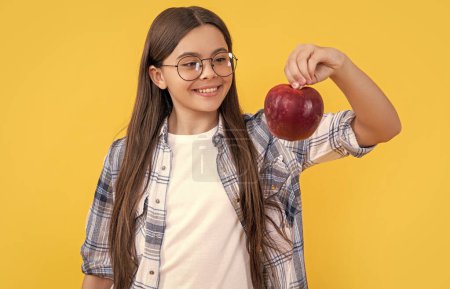 photo of happy teen girl with apple fruit. teen girl with apple isolated on yellow. teen girl with apple in studio. teen girl with apple on background.