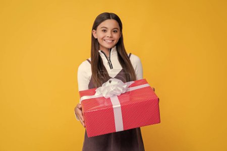 Téléchargez les photos : Smiling child with present box on yellow background. - en image libre de droit