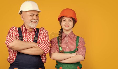 cheerful girl and grandfather builder in helmet on yellow background.