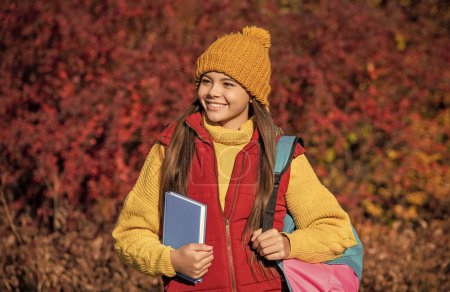 Lächelnde Schülerin kehrt im Herbst zur Schule zurück.