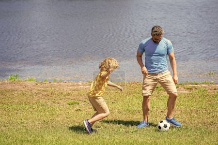 son has bonding time with father outdoor. Father and son enjoy a friendly game of football. happy childhood of son playing with father. father and son summer activity. experience of fatherhood.