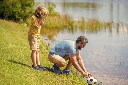 Father and son enjoy a friendly game of football. happy childhood of son playing with father. Outdoor fun. father and son summer activity. son has bonding time with father outdoor.