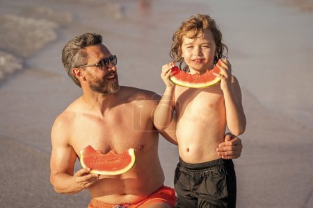father and son during summer childhood holiday eating watermelon at sea.