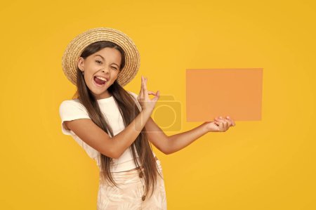 winking teen girl with copy space on orange paper on yellow background. ok.