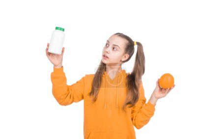 hard choice. choice between natural products and pills. presenting vitamin product. child with orange flavored pill. effervescent tablet for kids. girl hold multivitamin. organic food supplement.
