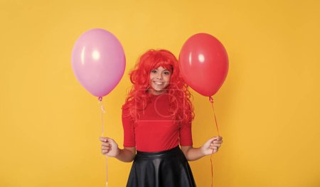 positive teen child with party balloon on yellow background.