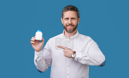 Photo for Man pointing finger on medication in studio. man presenting medication jar. photo of man holding medication, healthcare. man with medication isolated on blue background. - Royalty Free Image