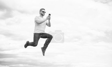 Photo for Man jump and chatting on smartphone on sky background. copy space. - Royalty Free Image