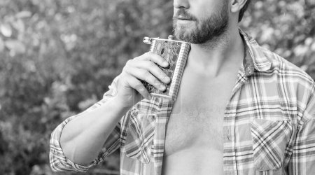 Photo for Man with bourbon hipflask, copy space. man with bourbon hipflask outdoor. man with bourbon hipflask wear checkered shirt. photo of man with bourbon hipflask. - Royalty Free Image