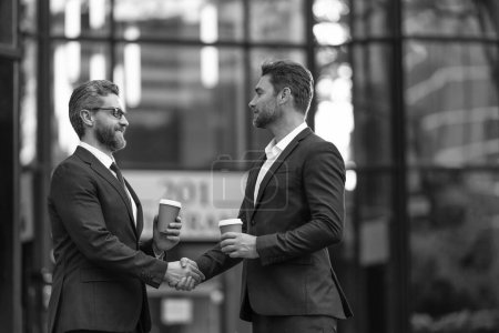 Photo for Cheerful two business partners dealing negotiation outdoor. two business partners hold coffee dealing negotiation. photo of two business partners dealing negotiation. two business partners dealing - Royalty Free Image