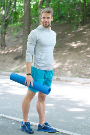 Fit your body. Yoga and Pilates. Sport man ready for workout. Healthy lifestyle. Fitness and sport. Yoga mat for training. Man in sportswear with fitness mat outdoor. Spiritual discipline.