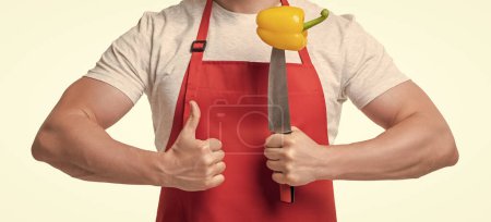 cropped view of man in apron with sweet pepper vegetable and knife isolated on white. thumb up.
