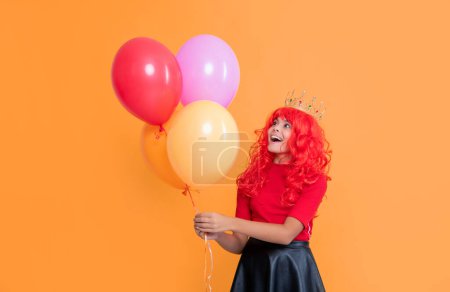 happy child in crown with party balloon on yellow background. wow.