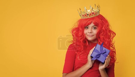 child smile in crown with gift box on yellow background.