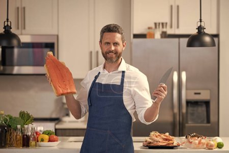 photo of man smile and cook delicacy salmon. man cook delicacy salmon. man cook delicacy salmon fish. man cook delicacy salmon in the kitchen.