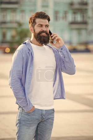 happy guy talk on smartphone outdoor. Draußen wird auf dem Smartphone geredet. Typen unterhalten sich auf der Straße per Smartphone. Foto vom Gespräch auf dem Smartphone.